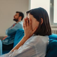 Woman covering face on a couch